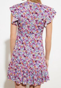 Květinové šaty s lila pozadím, s krátkými třásňovými rukávy, shromážděným volánkovým lemem a živým vícebarevným květinovým vzorem.