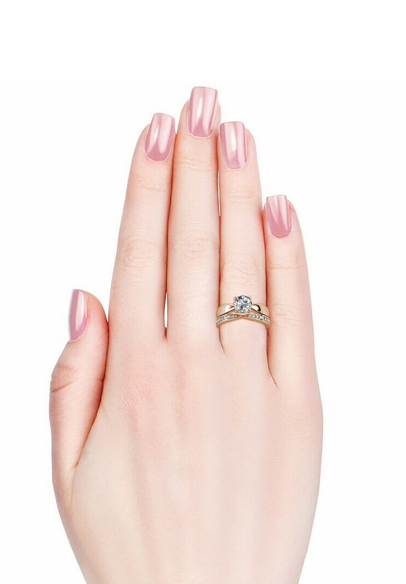 Gouden ringenset met een centrale ronde edelsteen en kleinere stenen langs een gedraaide band, tentoongesteld op een lichtbehaarde hand met roze nagels.