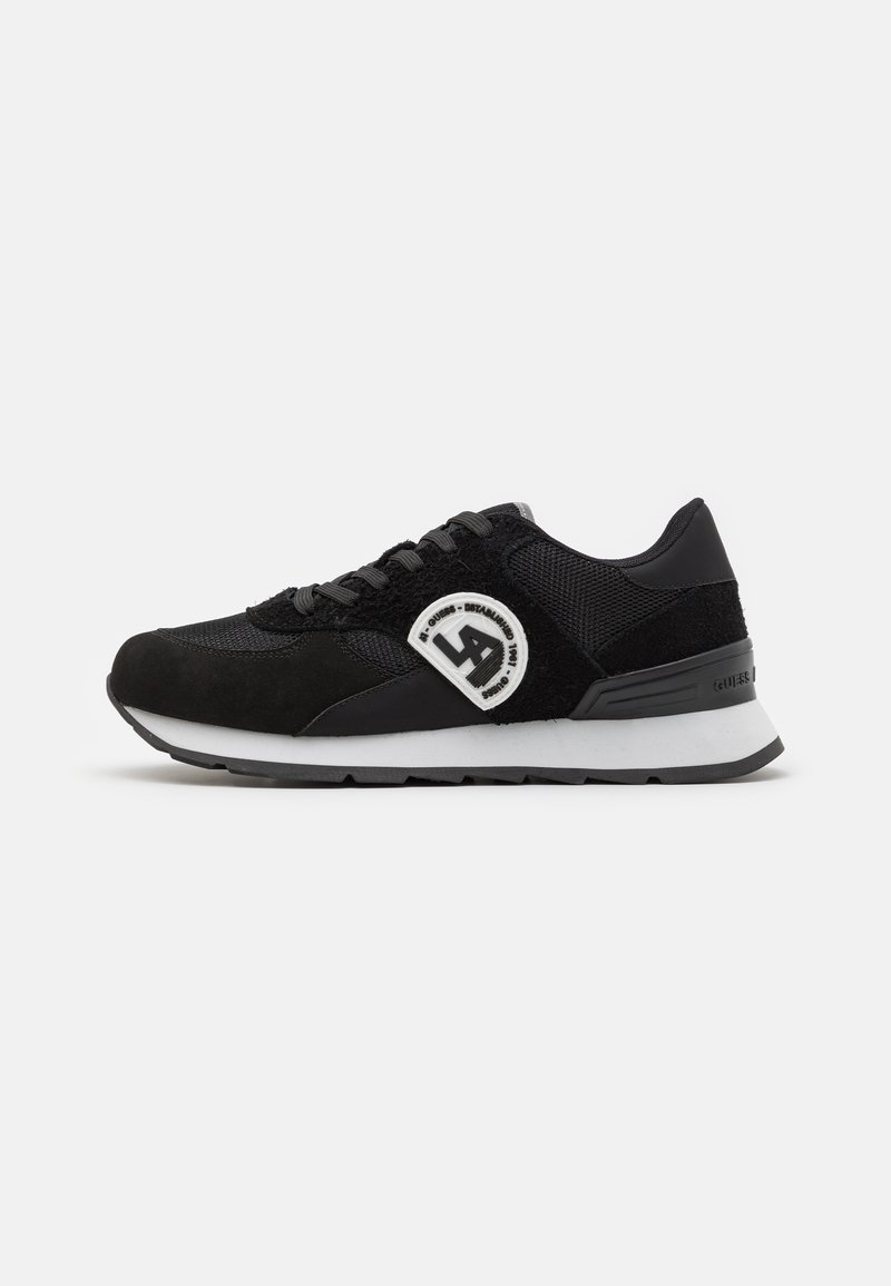 Scarpa sportiva nera con una combinazione di materiali in mesh e suede. Presenta una punta arrotondata, lacci, una suola intermedia bianca e un accento del logo.