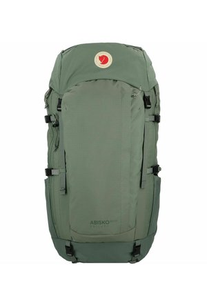 Grüner Stoff-Rucksack mit einer oberen Klappe, mehreren Schnallen und Seitentaschen. Verfügt über ein kreisförmiges Logo auf der Vorderseite und eine strukturierte Oberfläche.