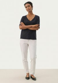 Tumman sininen V-kaula-aukkoinen t-paita, lyhyet hihat; vaaleat beige kapeat housut; mustat ballerinat; sileä kangas, minimalistinen muotoilu, ei näkyviä kuvioita.
