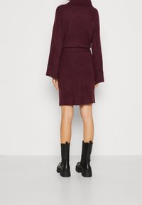 Burgundyröd stickad klänning med krage, långa ärmar och figursydd midja. Matchad med svarta ankelboots med en kraftig sula.