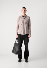 Camicia rosa chiaro a fantasia con bottoni, jeans neri a gamba larga e una borsa a tracolla in pelle nera. Design semplice con un'estetica casual.