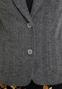 Texturované šedé sako se vzorem rybí kosti, jednorušné provedení, dvě knoflíky a kapsami, s přizpůsobeným střihem a upravenými klopami.