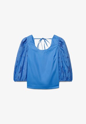 Blouse bleue à manches bouffantes en dentelle avec encolure dégagée, présentant des liens à nouer dans le dos, posée à plat sur un fond blanc.