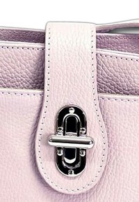Lichtroze leren handtas met sluiting, voorzien van een glanzende zilveren sluiting en nette stiksels langs de randen. Textuurdetails zichtbaar op het oppervlak.