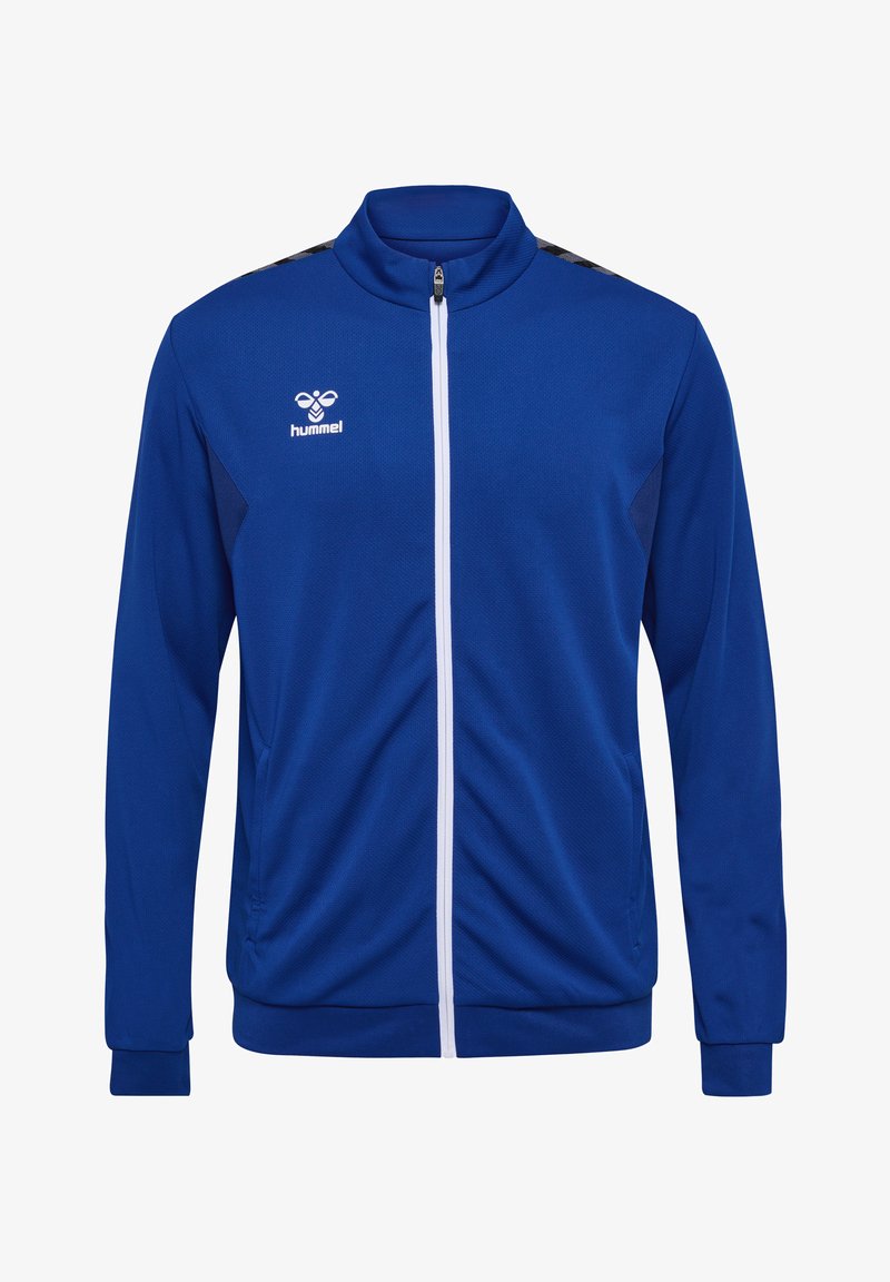 Veste zippée bleue en tissu léger avec poches latérales, panneaux sombres contrastants et fermeture éclair blanche. Dotée d'un logo sur le haut à gauche.