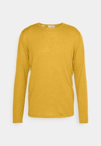 Långärmad, rundhalsad tröja i senapsgul färg gjord av mjukt tyg med en slät yta. Har en enkel, klassisk design utan utsmyckningar.