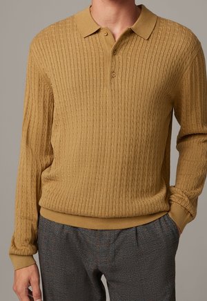 Żółty musztardowy pulower z dzianiny o prążkowanej fakturze, z długimi rękawami i kołnierzykiem. Posiada trzy guziki i dopasowany dół.