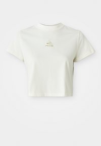 Kort hvit cropped t-skjorte med en liten beige Nike ACG-logo sentrert under halsringningen