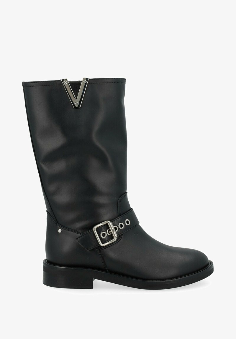 Stivale in pelle nera al ginocchio con un design strutturato, caratterizzato da una tracolla con fibbia argentata, accenti metallici e suola piatta.