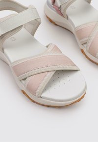 Sandalias ligeras con suela de goma blanca, correas de tela rosa y una plantilla acolchada con perforaciones para mayor transpirabilidad.