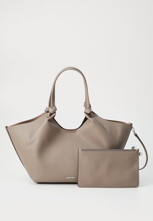 Velika bež kožna torba s čvorastim ručkama, koja ima glatku teksturu i odvojivu usklađenu torbicu. DKNY logo u srebrnoj boji na prednjoj strani.