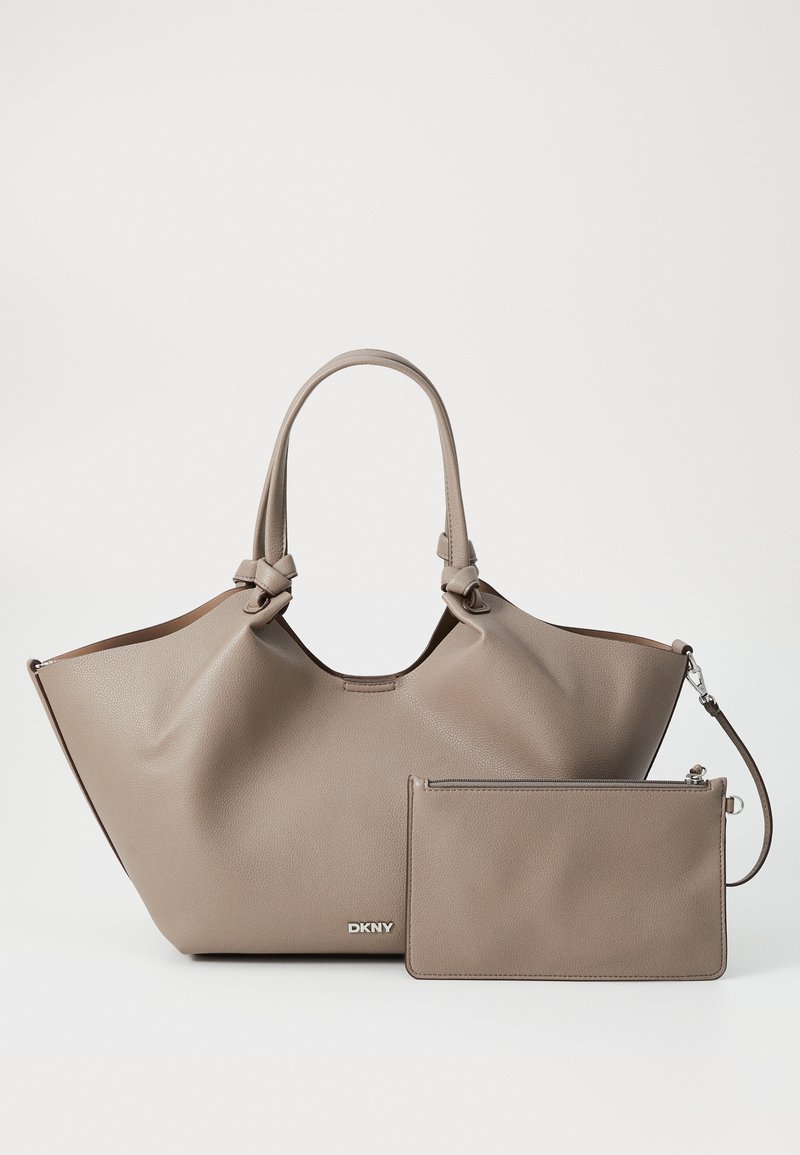 Stort beige lærremse med knyttede håndtak, med en glatt tekstur og en avtagbar matchende pouch. DKNY-logo i sølv på fronten.