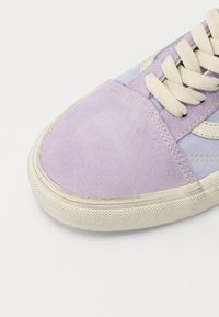 Baskets en suède violet avec un bout arrondi, lacets crème et semelle en caoutchouc texturée. Présente des accents bleu clair sur la tige.