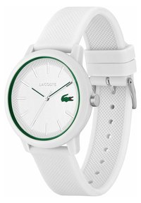 Montre blanche Lacoste avec un bracelet en silicone texturé blanc, boîtier rond, accent vert autour d'un cadran argenté, arborant un logo et de simples index horaires.
