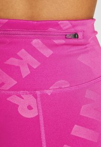 Leggings atletici aderenti rosa con una texture liscia, dotati di una zip nascosta e un motivo logo discreto su tutto il tessuto.