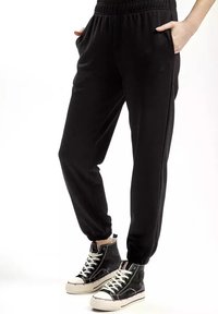 Czarne spodnie dresowe z elastycznym pasem oraz ribbowymi mankietami, z bocznymi kieszeniami i gładką, miękką fakturą.