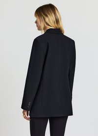 Blazer nero con un design su misura, spacchetto posteriore singolo e dettaglio delle maniche a tre bottoni. Tessuto liscio e taglio dritto per un aspetto strutturato.