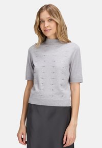 Jasnoszary sweter z krótkim rękawem i wysokim kołnierzem, zdobiony fakturowanym wzorem oraz metalicznymi akcentami. Miękka dzianina; dopasowany krój.