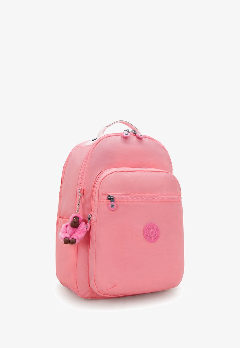 Różowy plecak nylonowy o zaokrąglonym kształcie, z podwójnymi zamkami błyskawicznymi, przednią kieszenią i akcentem w postaci breloczka w kształcie małpki.