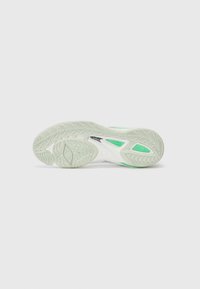 Athletic shoe sole with a textured rubber surface, featuring a white base, green accents, and a distinctive traction pattern.