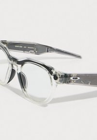 Clear frame eyewear with rounded lenses. Features a combination of transparent and gray materials, with a small camera integrated into the design.