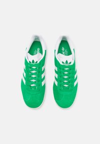 Green athletic shoes with white stripes; suede upper, lace closure, and cushioned collar. Green insole with brand logo. Rubber outsole.