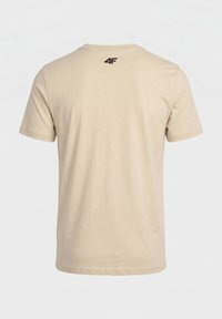 T-shirt beige à manches courtes vu de dos avec un petit logo noir "4F" au niveau du col.