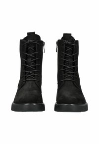 Par de botas de tobillo de ante negro con punteras redondas, cordones en la parte delantera, cremalleras laterales y suelas de goma planas, mirando hacia adelante sobre un fondo blanco.