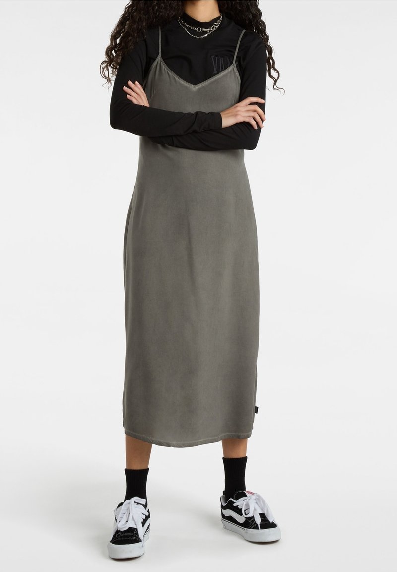 Vestido midi gris con tirantes finos, hecho de una tela suave, combinado con una blusa de manga larga negra y zapatillas blanco y negro.