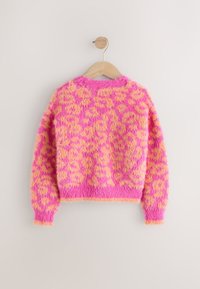 Plysset pullovertrøje i skrigende pink med orange leopardpletter, med rund hals og ribbede manchetter, hængende på en træknage.