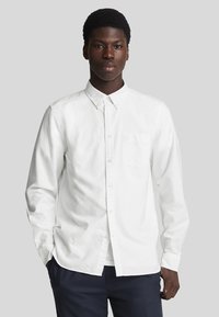 Witte overhemd met lange mouwen, kraag en een borstzak. Gemaakt van een gladde stof, met een relaxte pasvorm en minimale details.