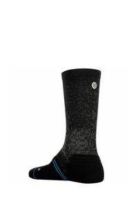 Schwarzer Crew-Socken mit grauen Sprenkeln, einem kleinen runden Logo nahe der Oberseite und einem dünnen blauen Streifen im Bereich des Fußgewölbes.