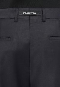 Calças cinza-escuro com uma textura suave, apresentando dois bolsos frontais, um corte slim e uma etiqueta com a inscrição "KARL LAGERFELD" na cintura.