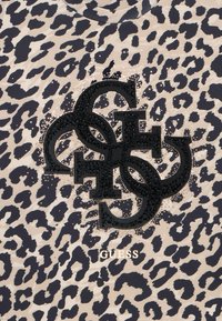 Tessuto con stampa leopardata e accenti neri del logo, caratterizzato da lettere sovrapposte e decorazioni brillanti. Testo "GUESS" nella parte inferiore.
