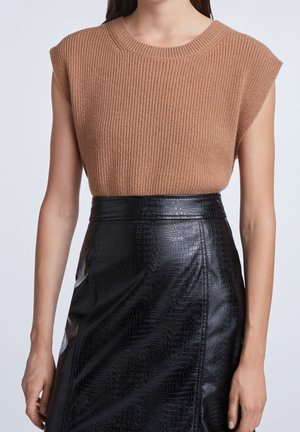 Beżowy prążkowany krótki sweter z krótkim rękawem, zestawiony z czarną ołówkową spódnicą z ekologicznej skóry o wzorze krokodyla i dopasowanym kroju.