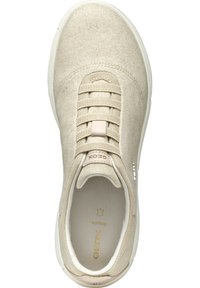 Zapatilla de tela beige con un upper texturizado, cierre de cordones elásticos y suela de goma blanca. Presenta un logo de la marca y una plantilla acolchada.