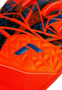 Gant de sport orange vif avec des accents noirs et bleus, présentant une surface texturée et des motifs géométriques pour une meilleure prise en main et une protection accrue.