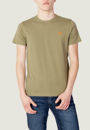 T-shirt in cotone verde oliva con maniche corte e scollatura rotonda, con un piccolo logo arancione sul lato sinistro del petto. Indossato con jeans blu.