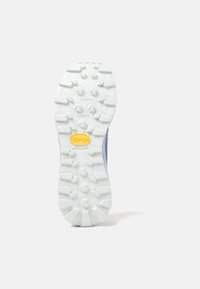 Suela exterior de goma blanca con patrón de agarre texturizado y tacos hexagonales, con un logotipo amarillo de "Vibram Megagrip" en el centro.