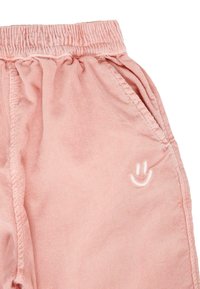 Roze katoenen broek met een elastische tailleband, voorzien van zijzakken en een kleine witte geborduurde glimlachende gezicht. Zachte, gestructureerde stof.