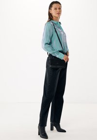 Licht teal blouse met een luchtige textuur, gecombineerd met hoge zwarte broeken met knoopdetails, en stijlvolle zwarte haklaarzen. 