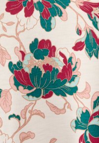Tessuto floreale con grandi fiori in teal e burgundy, accenti rosa e sfondo crema chiaro. Mostra dettagli intricati e una texture morbida.