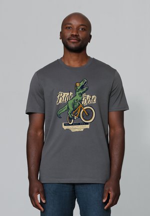 Grijze T-shirt met korte mouwen met een graphic van een dinosaurus die op een fiets rijdt, met kleurrijke tekst en designelementen op een lichtere achtergrond.