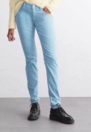 Lyseblå slim-fit jeans laget av bomullsblanding med en jevn tekstur. Brukt med svarte snøringer, som har tykke såler.