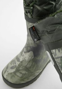 Grüne wasserdichte Stiefel mit gepolstertem Obermaterial und Camouflage-Muster. Verfügt über 3M-Isolierung und eine strukturierte Gummisohle für guten Halt.