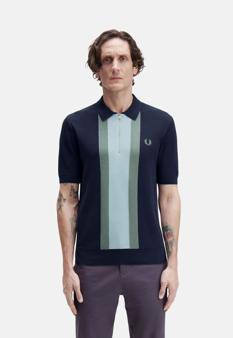 Polo shirt navy de manga corta, con rayas verticales en verde y azul claro, un cierre de cremallera y un logo bordado en el pecho.