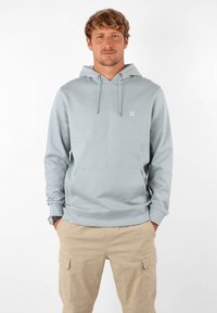 Haut à capuche bleu clair avec une poche kangourou à l'avant, des poignets et un ourlet côtelés. Comprend des cordons avec embouts en métal et un petit logo sur la poitrine.