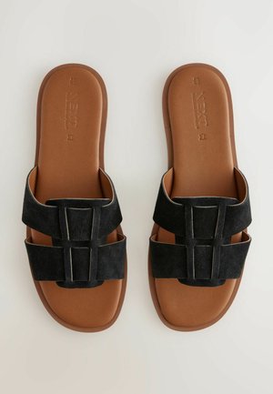 Zwarte suède slip-on sandalen met twee brede banden en vierkante gespsaccenten, voorzien van een bruine gevoerde zool voor extra comfort.
